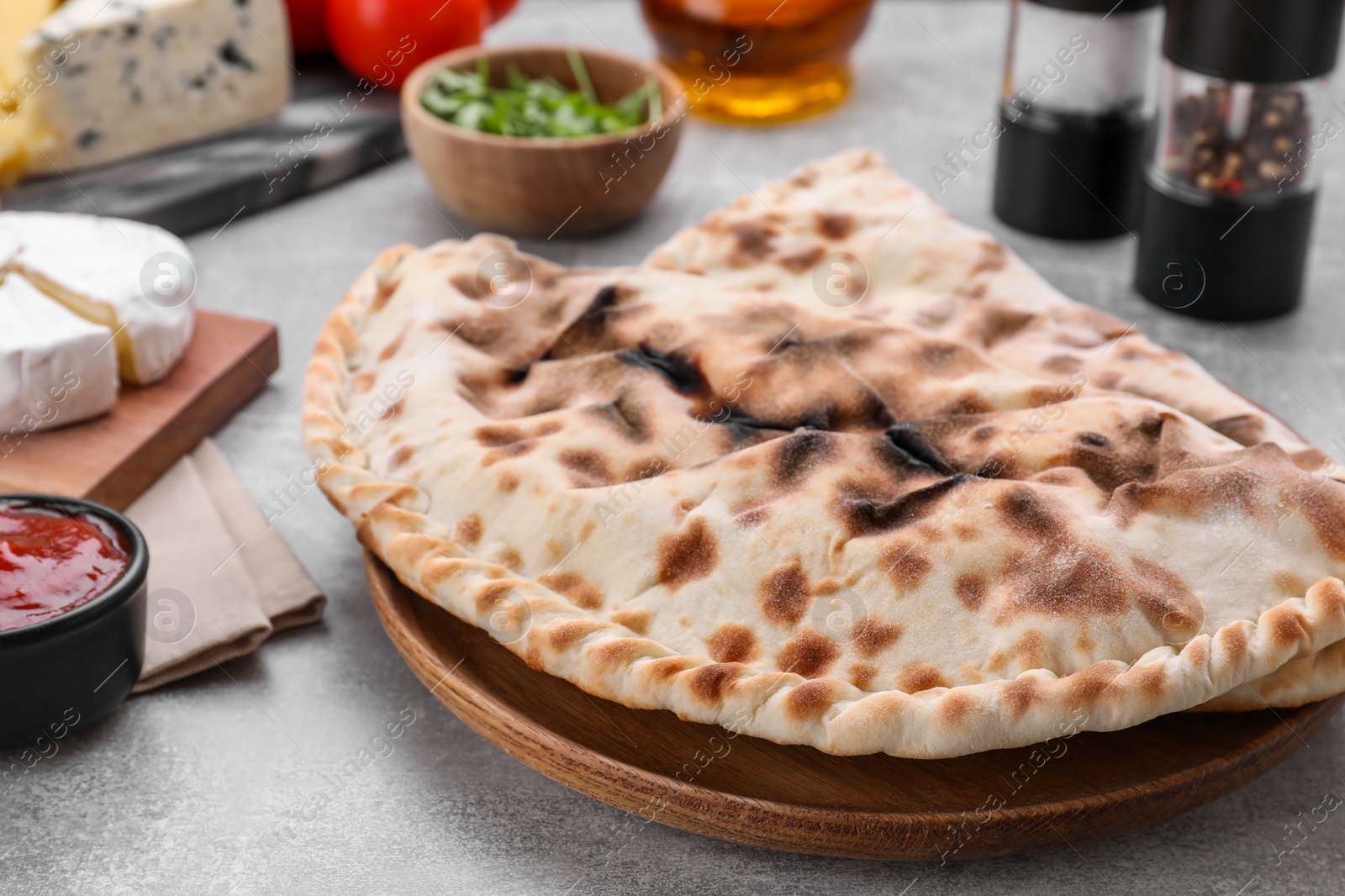 Photo of Tasty pizza calzones and different products on light grey table