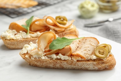 Board with delicious chicken bruschettas on table, closeup