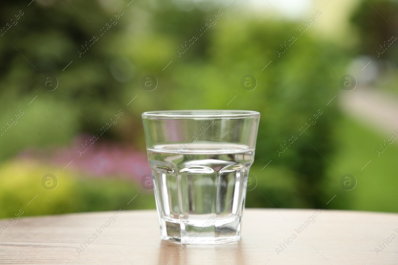 Photo of Glass of fresh water on wooden table outdoors