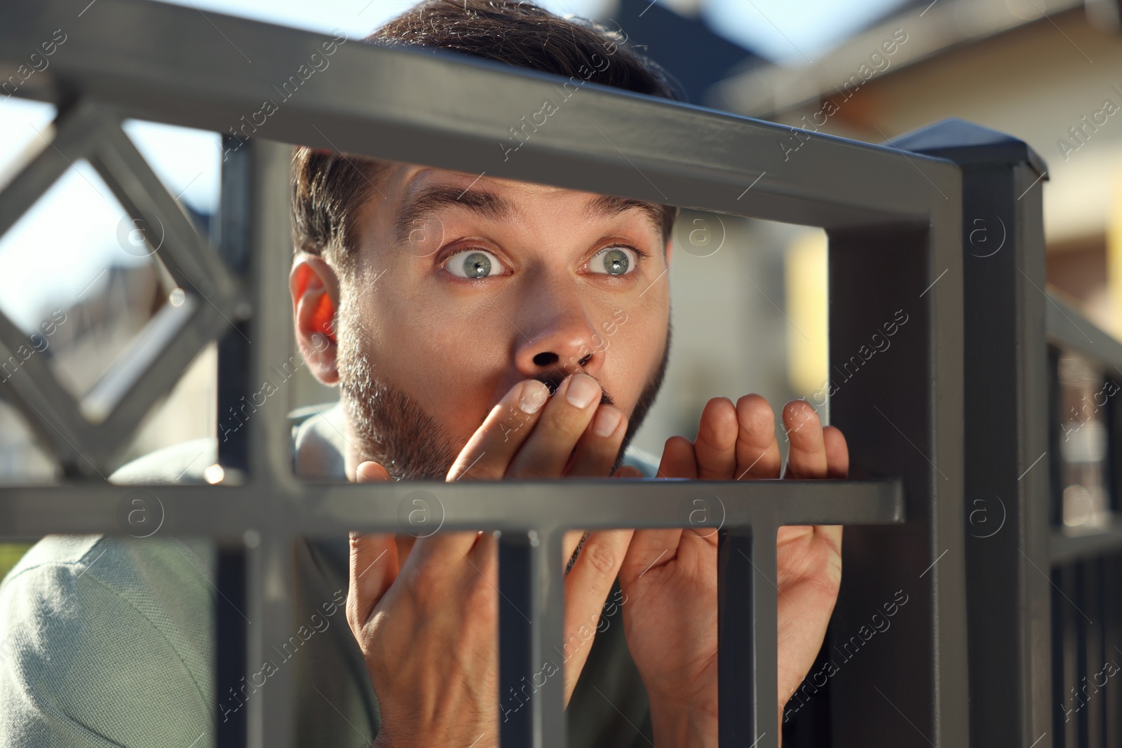 Photo of Concept of private life. Curious man spying on neighbours over fence outdoors