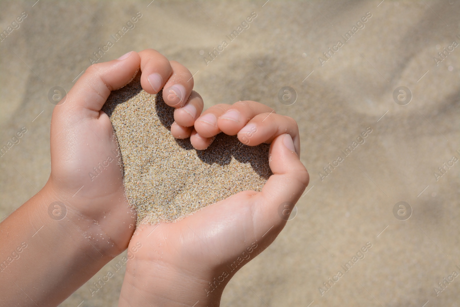 Photo of Child holding sand in hands outdoors, closeup. Fleeting time concept