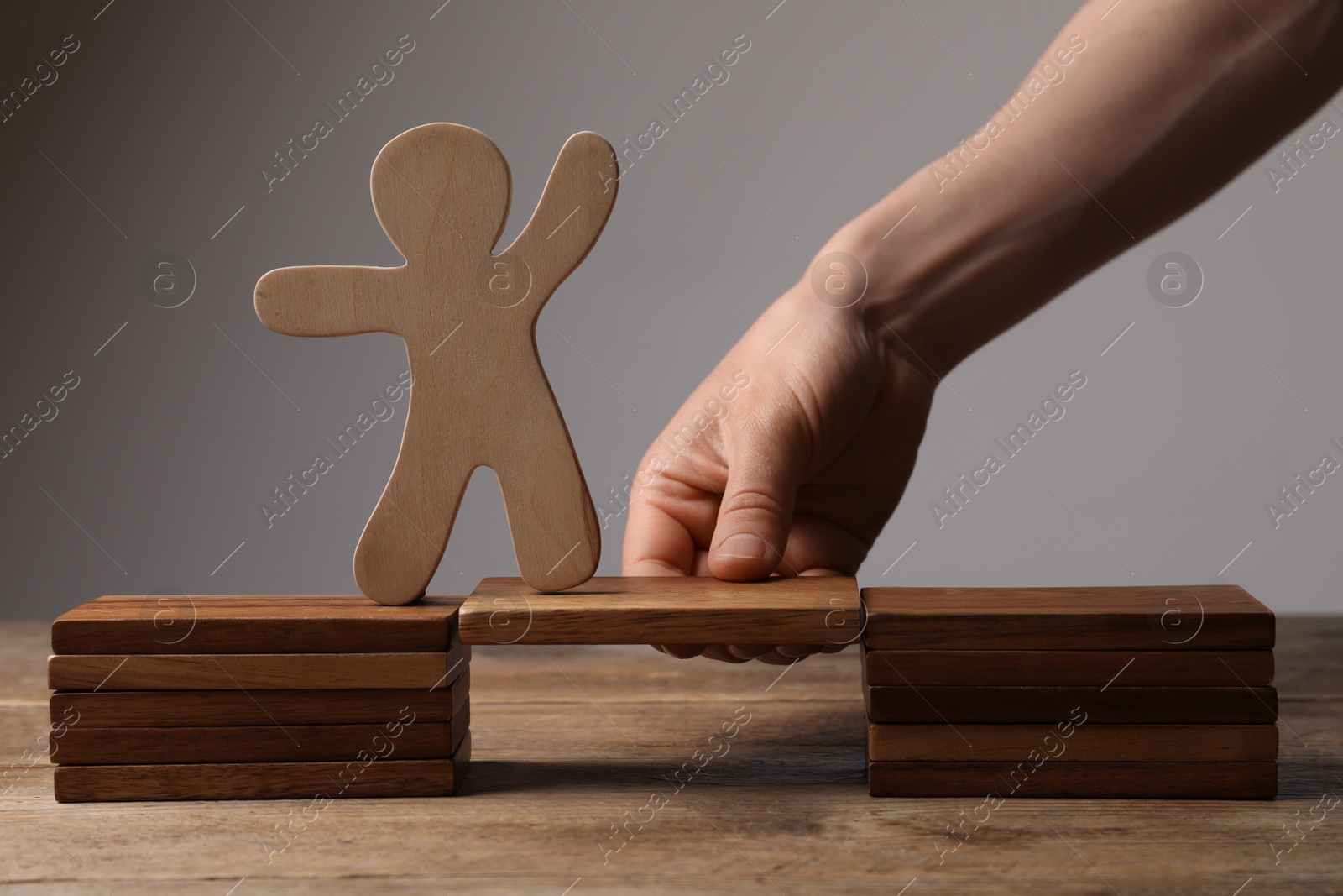 Photo of Woman holding wooden block with human figure at table, closeup