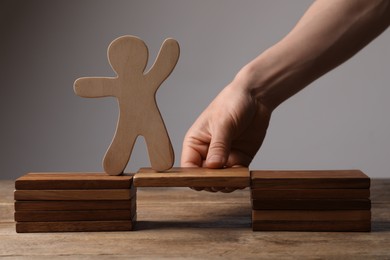 Woman holding wooden block with human figure at table, closeup