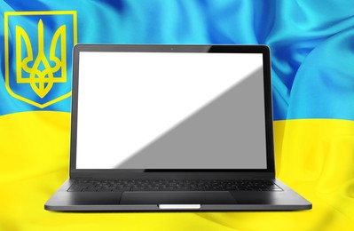 Laptop with blank screen and Ukrainian national flag on background