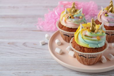 Photo of Cute sweet unicorn cupcakes on white wooden table, space for text