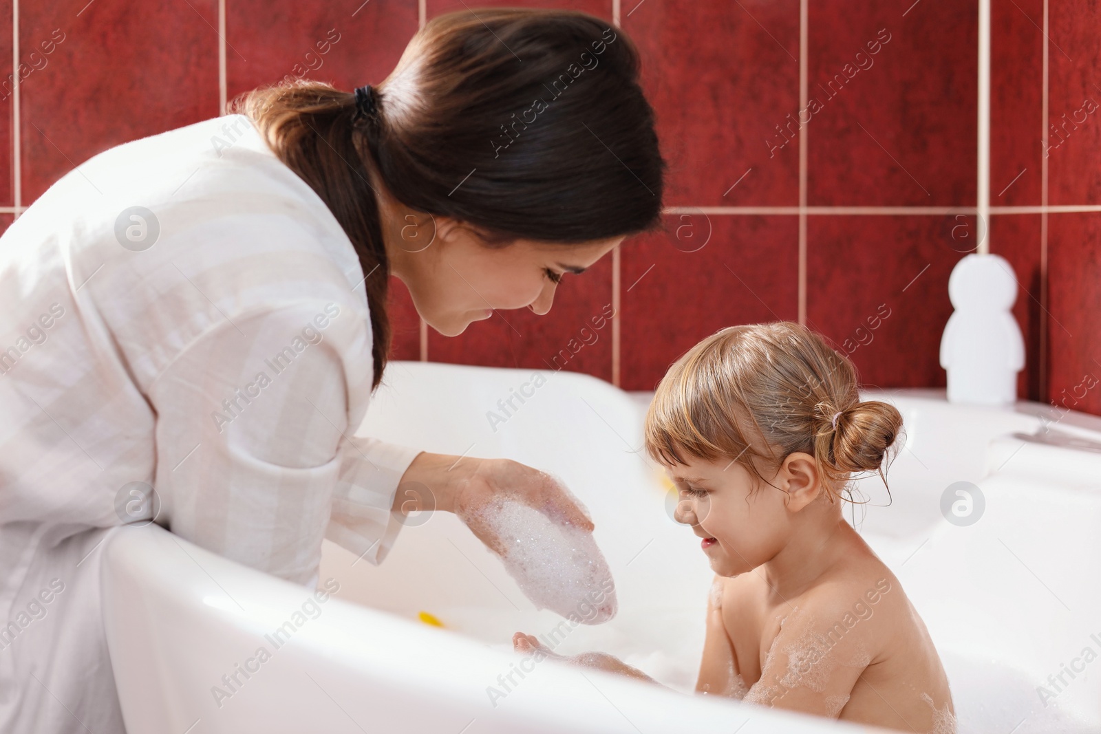 Photo of Mother with her little daughter spending time together in bathroom