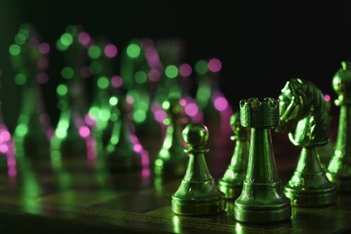 Photo of Chess pieces on checkerboard in color light, selective focus. Space for text