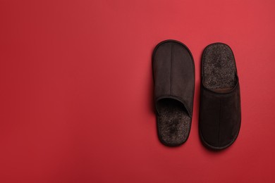Photo of Pair of brown slippers on red background, top view. Space for text
