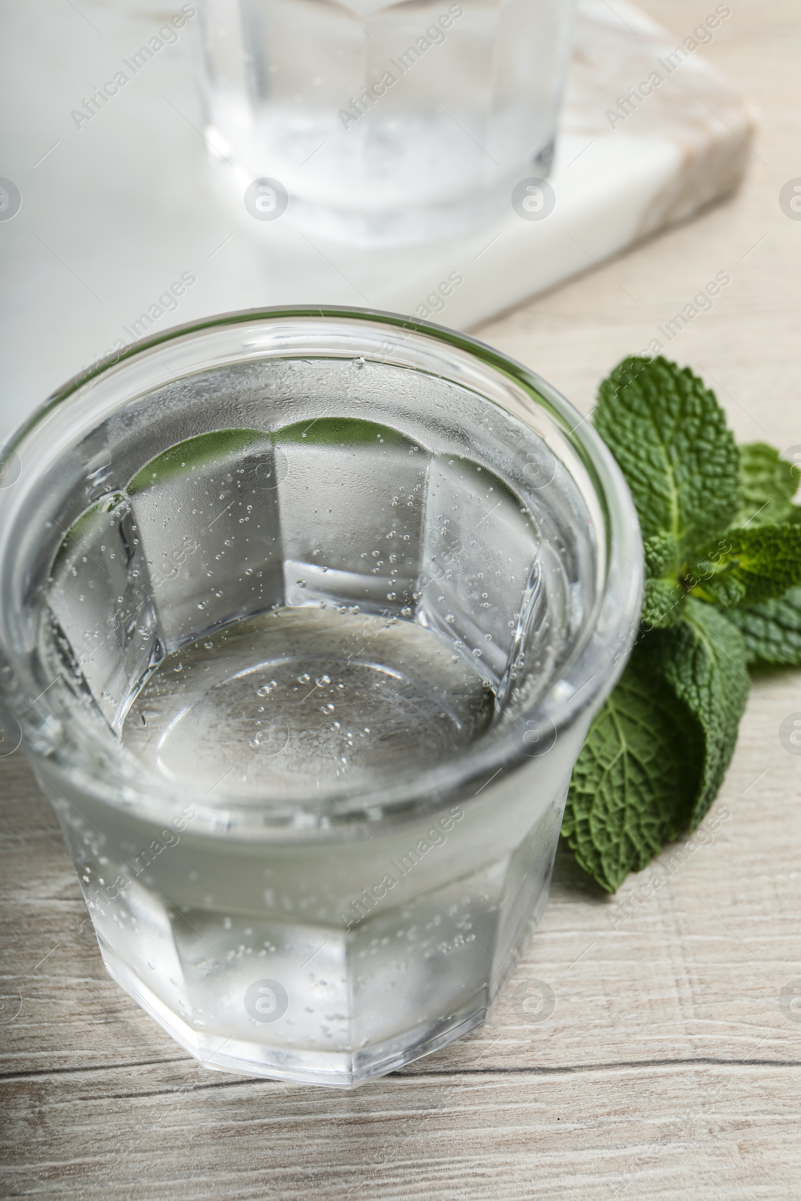 Photo of Glass of soda water and mint on white wooden table