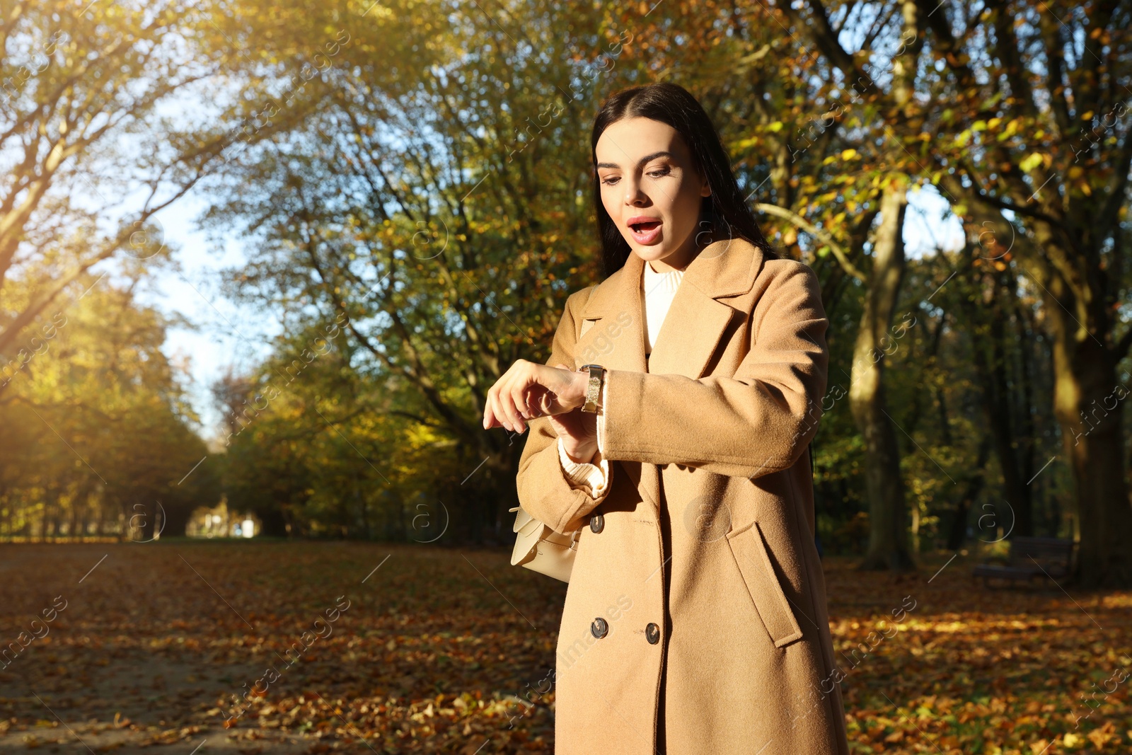 Photo of Emotional woman checking time on watch in park. Being late concept