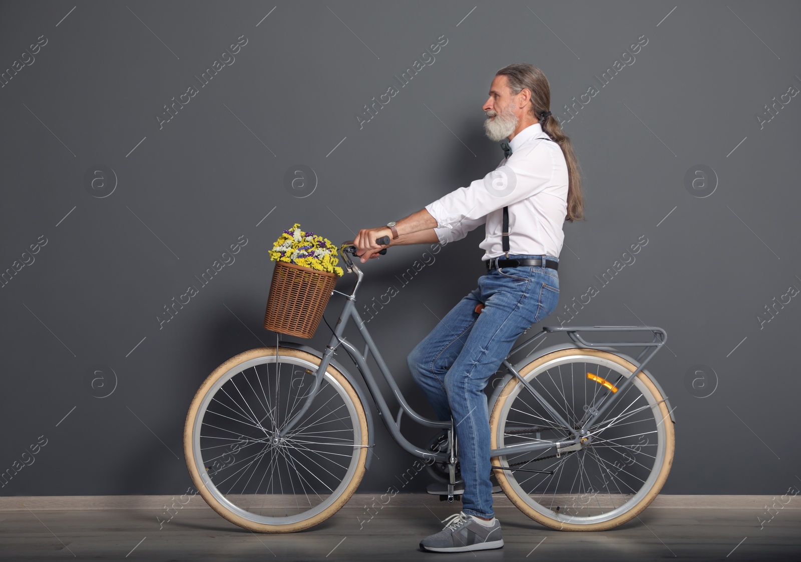 Photo of Portrait of handsome mature man with bicycle near color wall