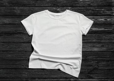 Photo of Stylish white t-shirt on black wooden background, top view