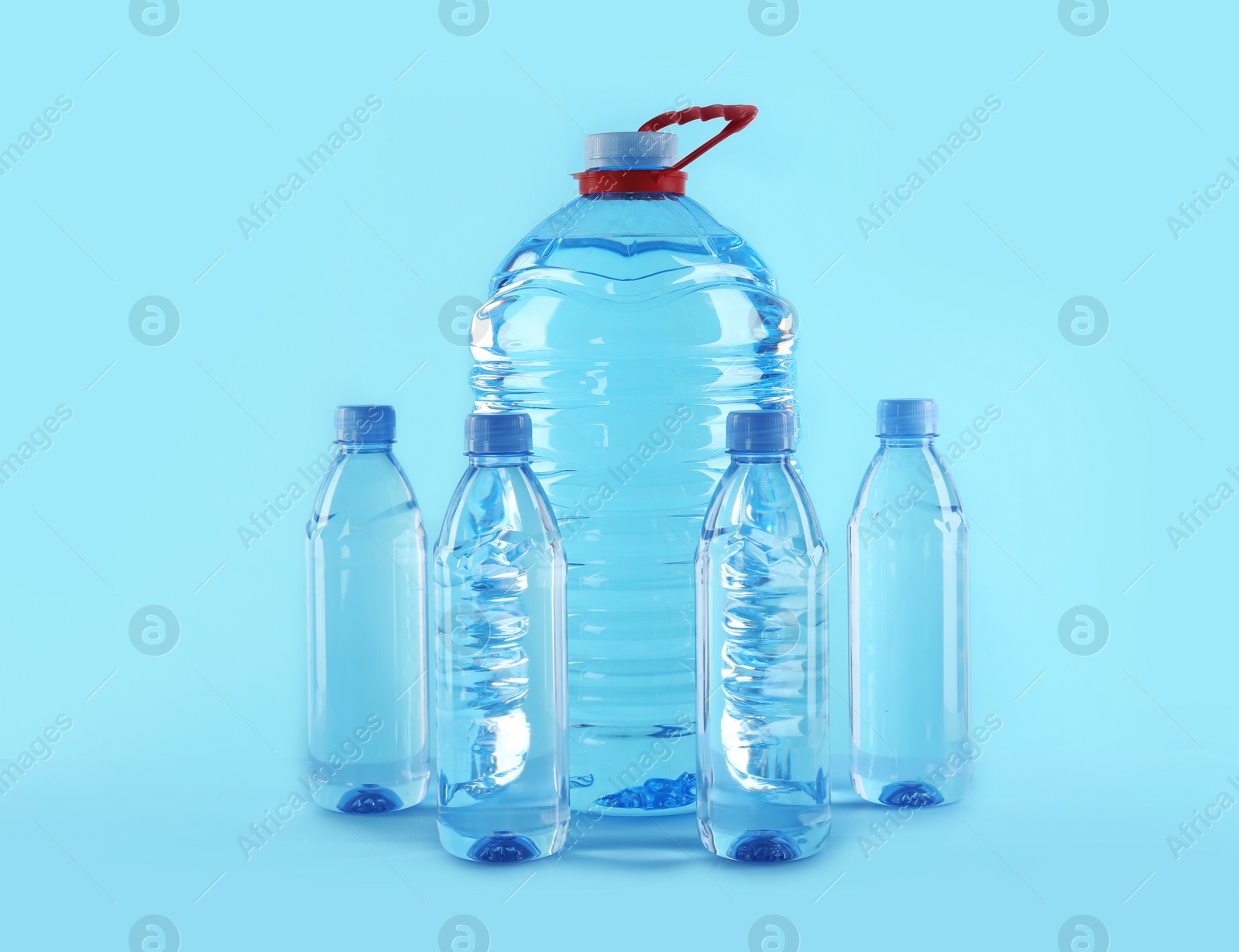 Photo of Large and small bottles with pure water on color background