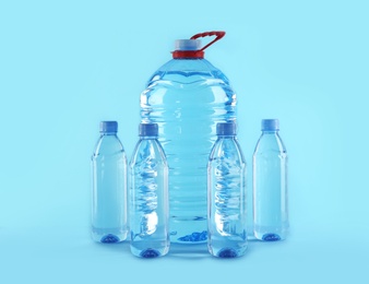 Large and small bottles with pure water on color background