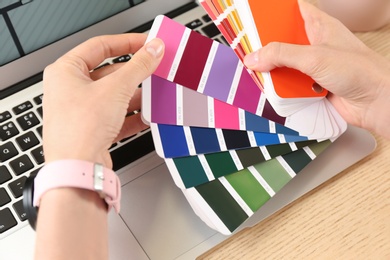 Photo of Woman with palette samples at wooden table, closeup