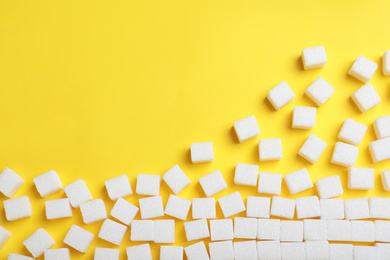 Photo of Refined sugar cubes on yellow background, top view. Space for text