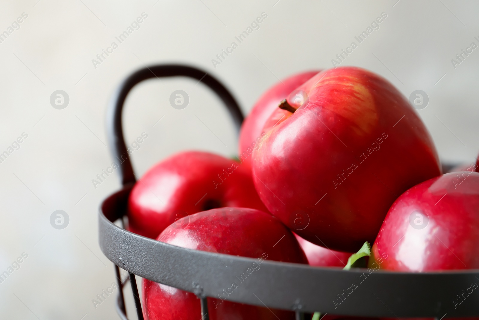 Photo of Basket with fresh ripe red apples on light background, closeup