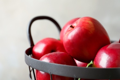 Basket with fresh ripe red apples on light background, closeup