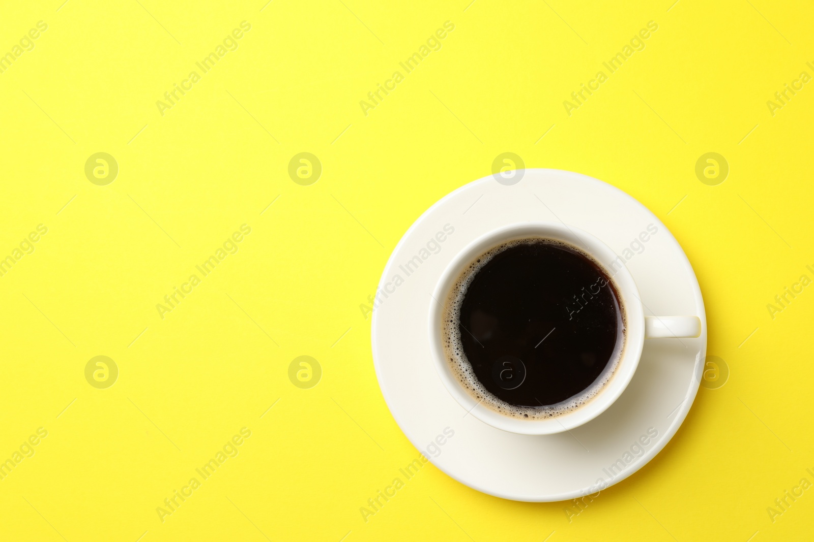 Photo of Cup of aromatic coffee on yellow background, top view. Space for text