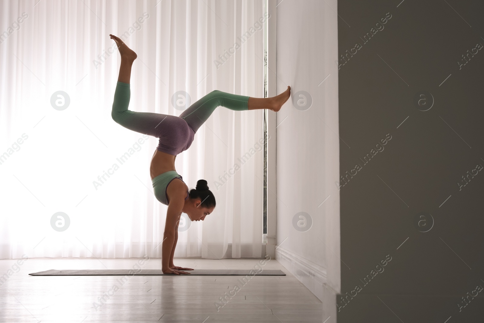 Photo of Woman practicing downward facing tree asana in yoga studio. Adho mukha vrksasana pose