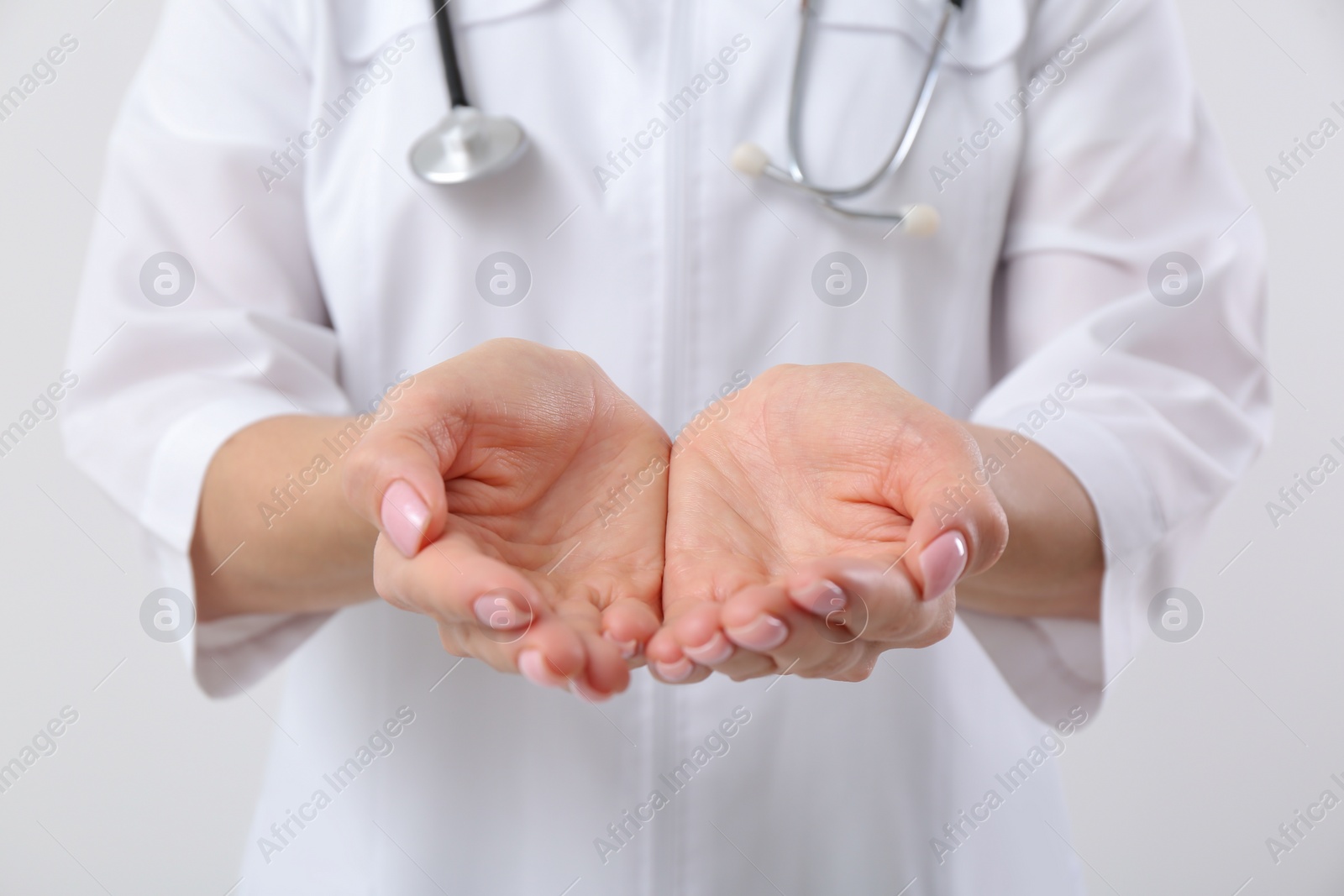 Photo of Doctor with stethoscope holding something on white background, closeup. Cardiology concept