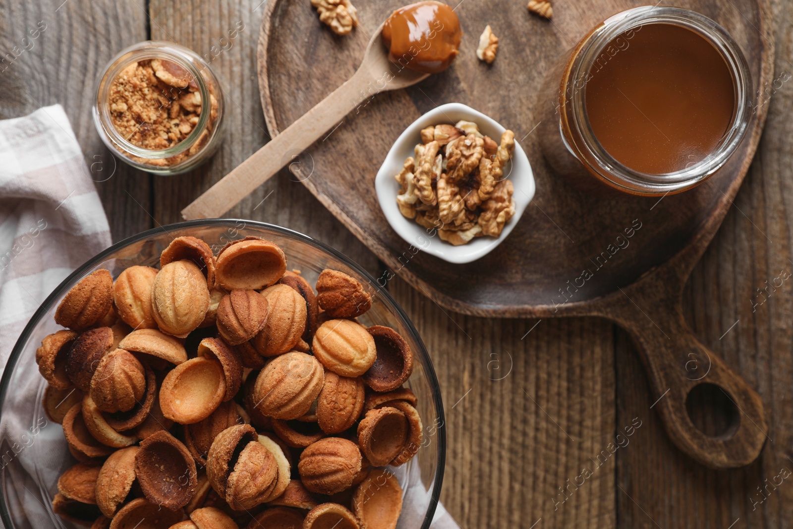 Photo of Making walnut shaped cookies. Cooked dough, caramelized condensed milk and nuts on wooden table, flat lay