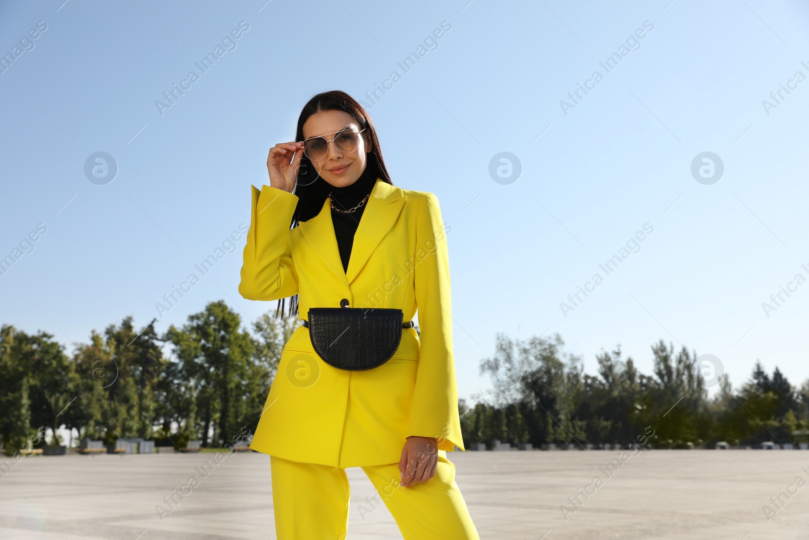 Photo of Beautiful young woman with stylish waist bag on city street