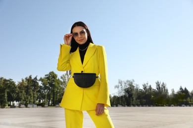 Photo of Beautiful young woman with stylish waist bag on city street