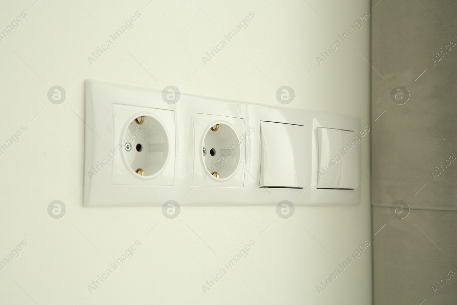 Photo of Light switches and power sockets on white wall indoors