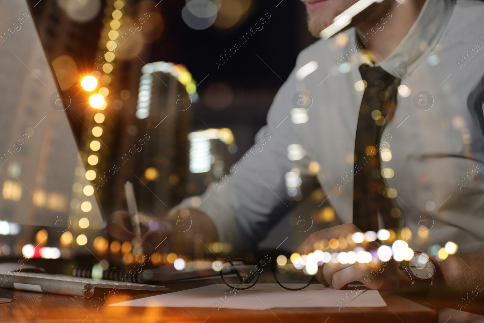 Image of Double exposure of night cityscape and young man working in office, closeup. Financial analytics