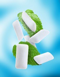 Image of Fresh mint leaves and chewing gum pads falling on light blue background