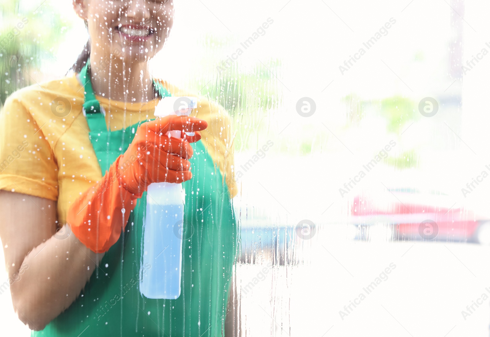 Photo of Female worker washing window glass from outside