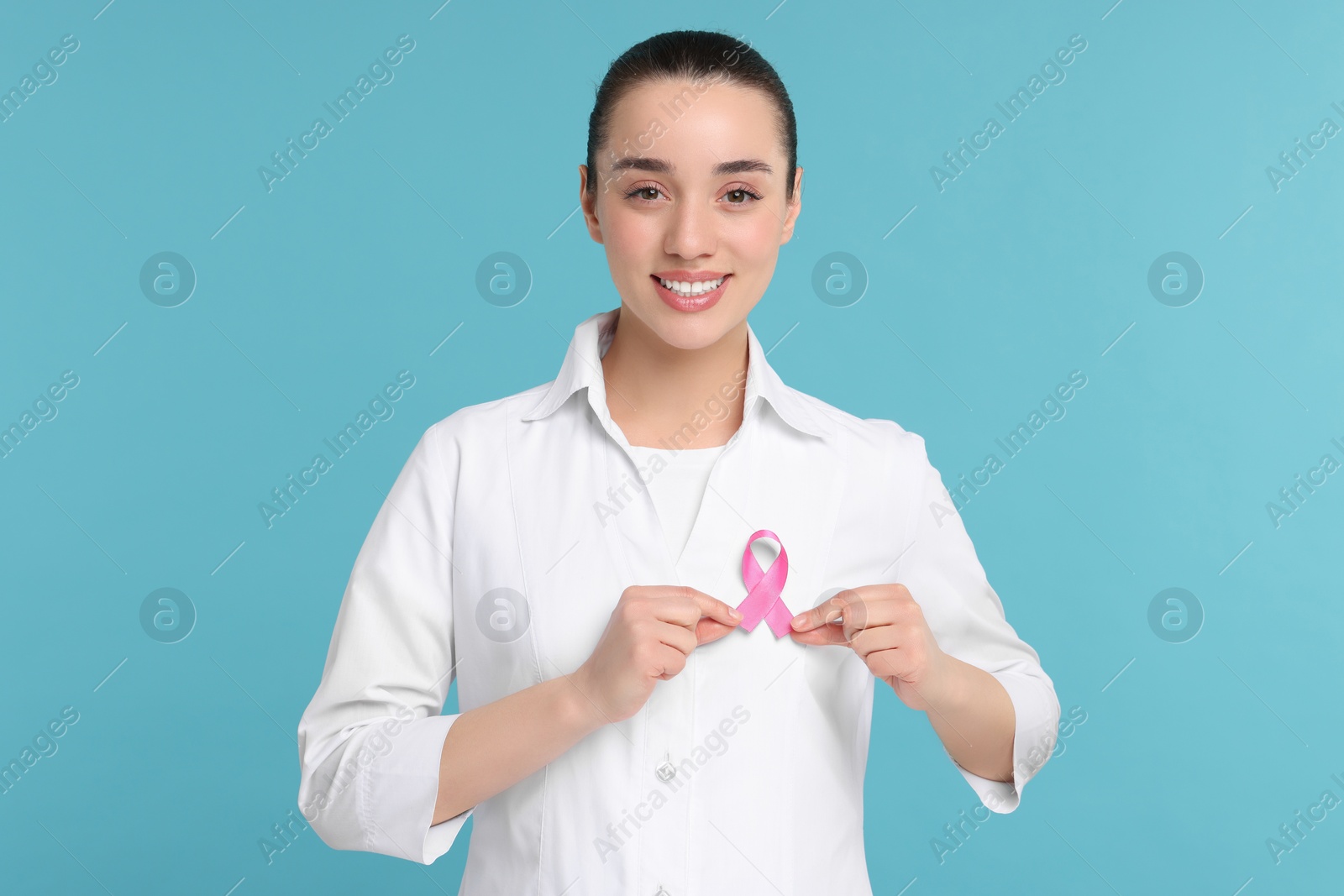 Photo of Mammologist with pink ribbon on light blue background. Breast cancer awareness