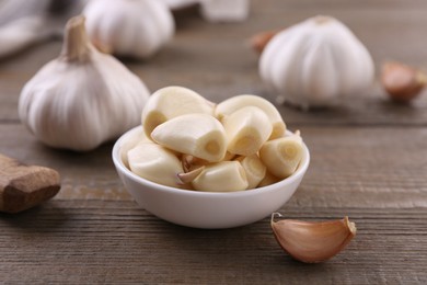 Photo of Aromatic garlic cloves and bulbs on wooden table, closeup