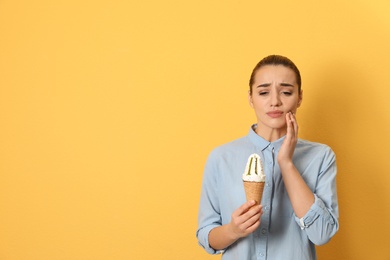 Photo of Emotional young woman with sensitive teeth and ice cream on color background. Space for text