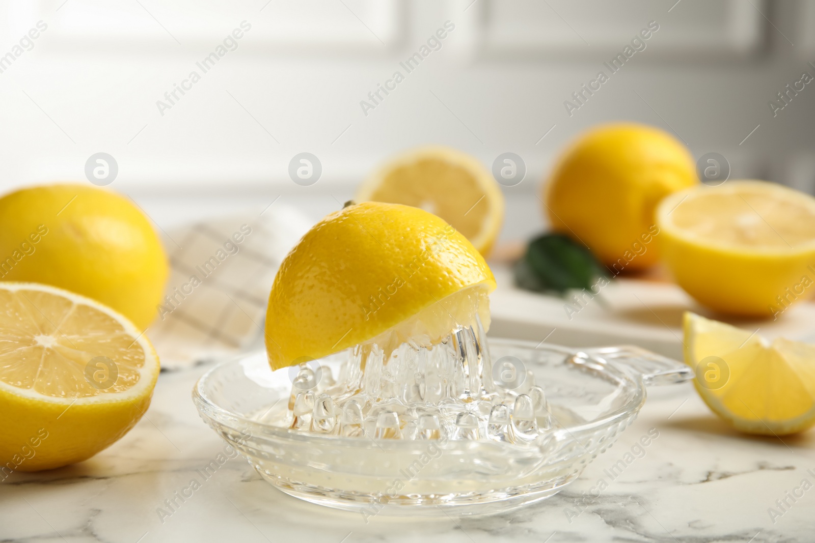Photo of Glass squeezer and fresh lemons on white marble table