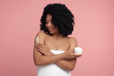 Photo of Young woman applying body cream onto shoulder on pink background