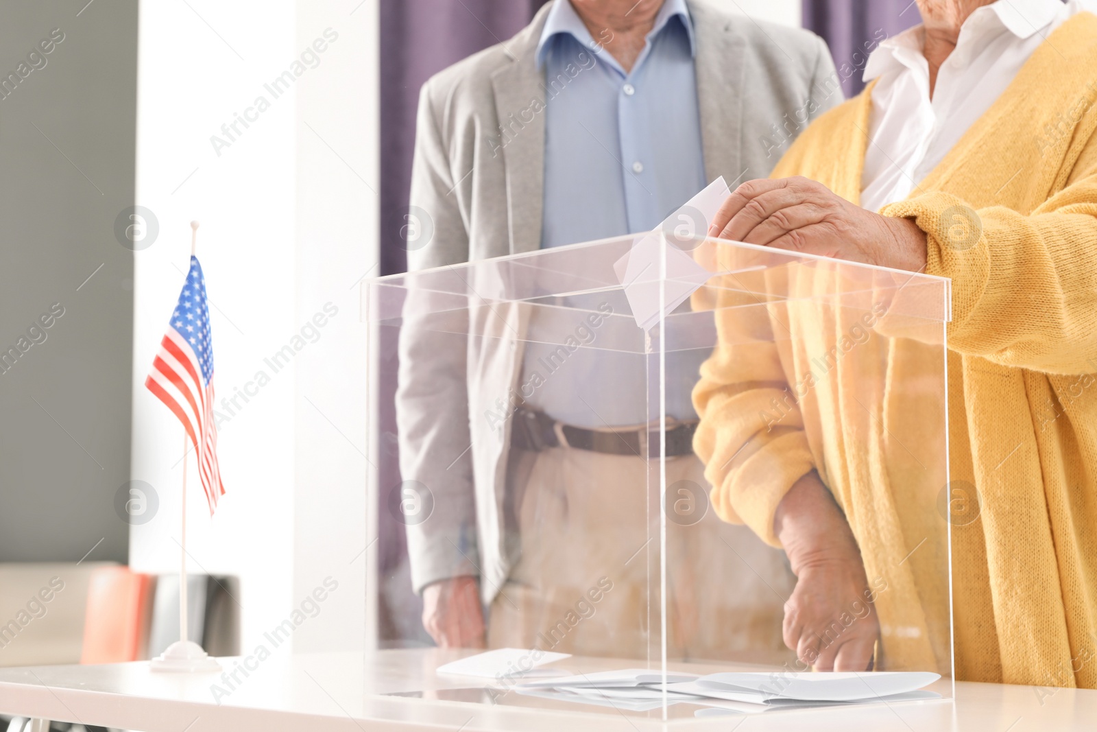 Photo of Elderly woman putting ballot paper into box at polling station