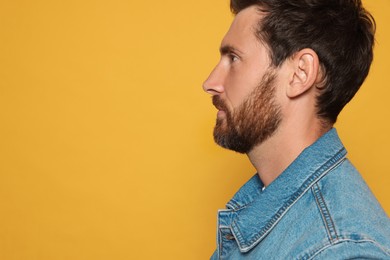Photo of Profile portraitbearded man on orange background. Space for text