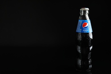Photo of MYKOLAIV, UKRAINE - FEBRUARY 08, 2021: Glass bottle of Pepsi with water drops on black background. Space for text