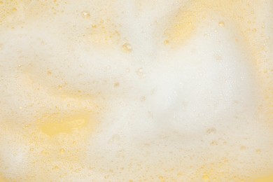 White washing foam on yellow background, top view
