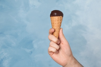 Photo of Man holding yummy ice cream on color background. Focus on hand
