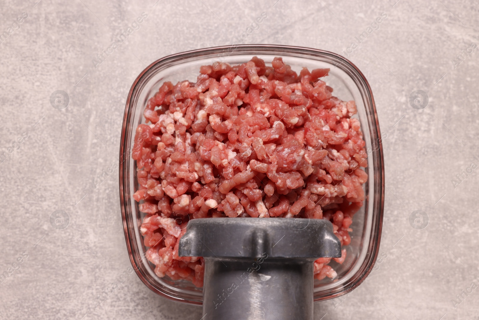 Photo of Manual meat grinder with beef mince on light grey table, top view