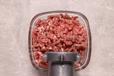 Photo of Manual meat grinder with beef mince on light grey table, top view