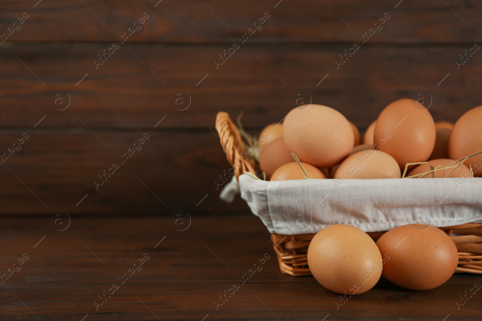 Photo of Raw chicken eggs on wooden table. Space for text