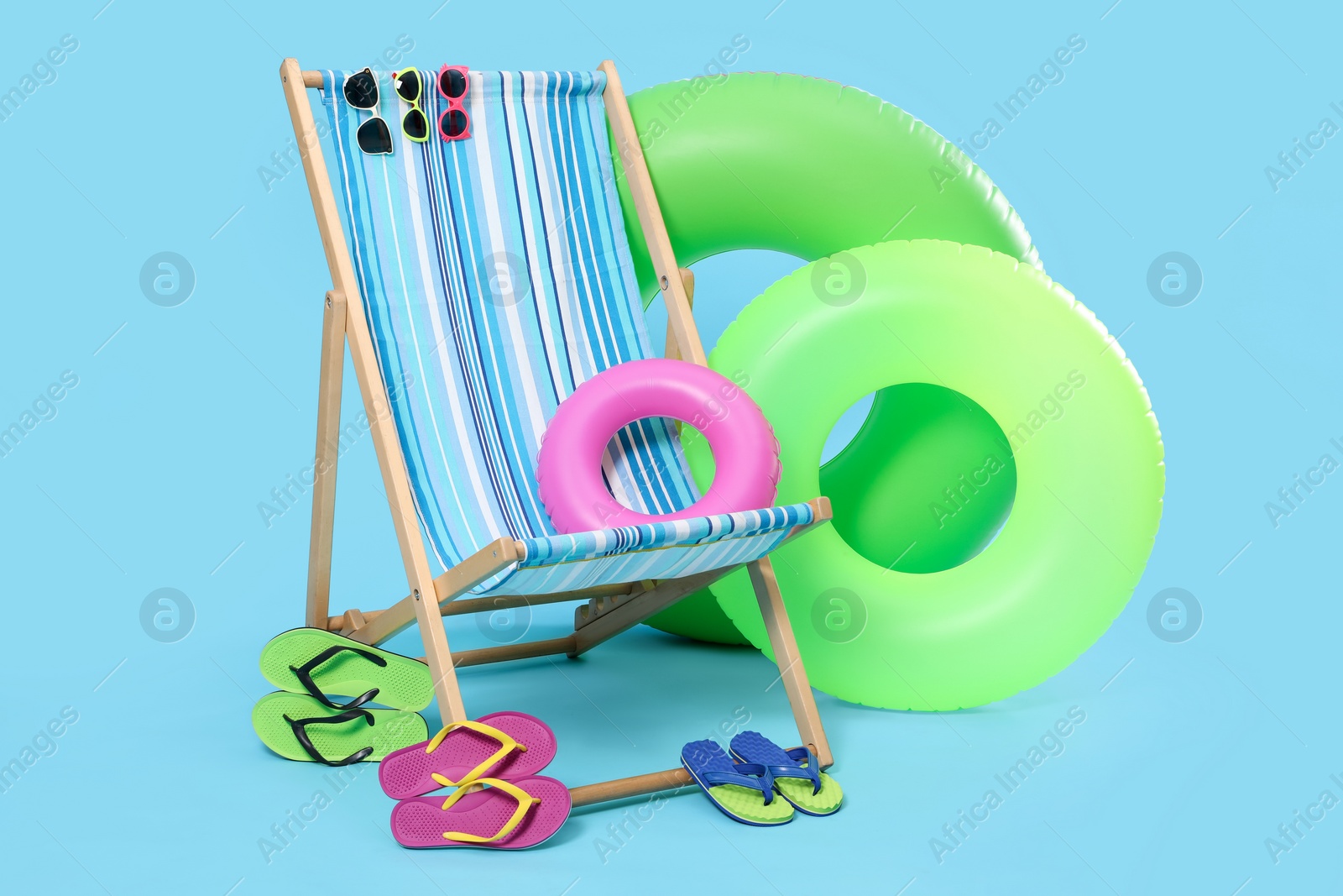 Photo of Deck chair and beach accessories on light blue background