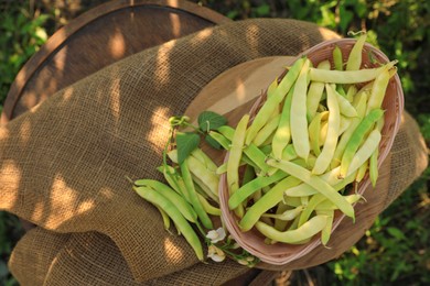 Photo of Wicker basket with fresh green beans on wooden chair in garden, top view