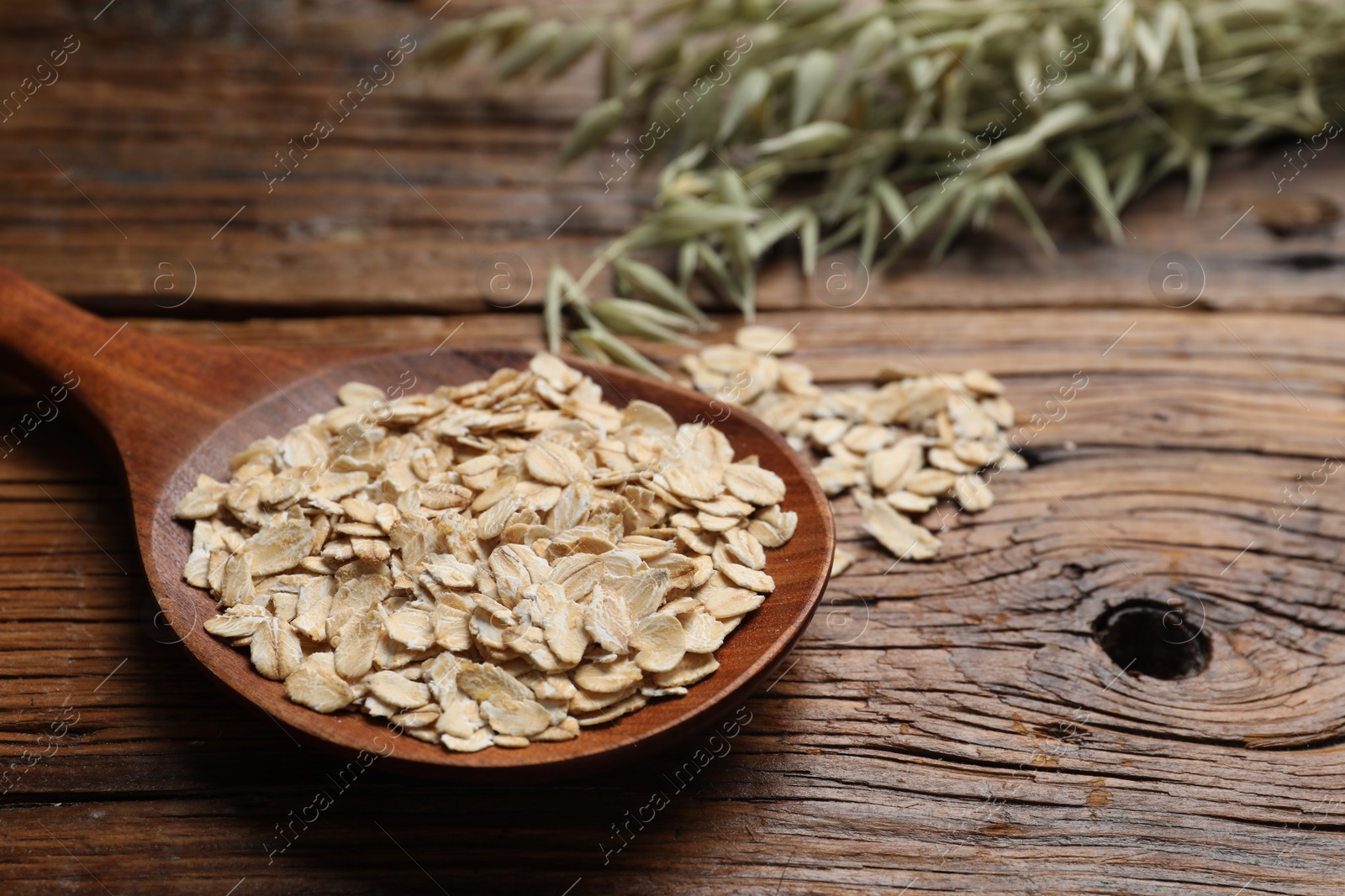 Photo of Spoon with oatmeal and florets on wooden table, closeup. Space for text