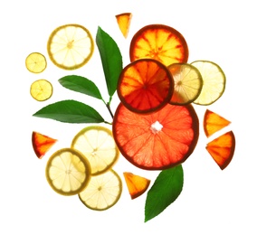 Illuminated slices of citrus fruits and leaves on white background, top view