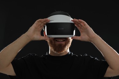 Smiling man using virtual reality headset on black background